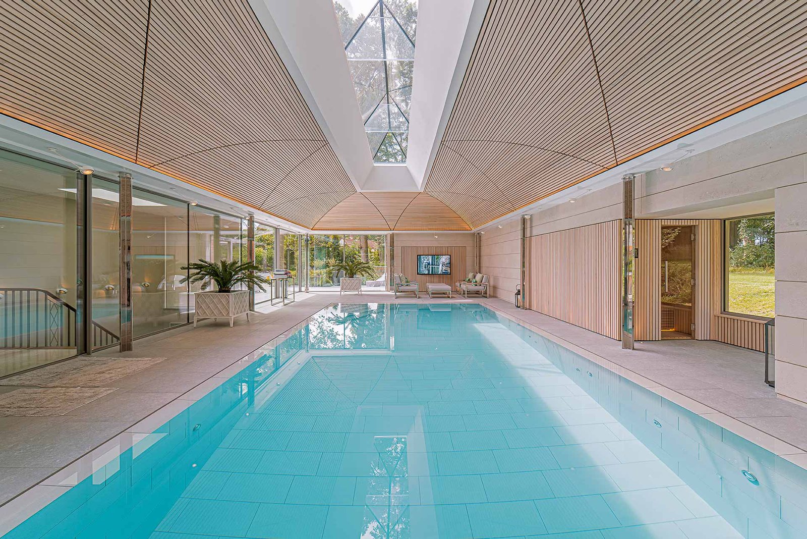Luxury indoor pool room with fully invisible Amina speakers built into the ceiling — no visible grilles