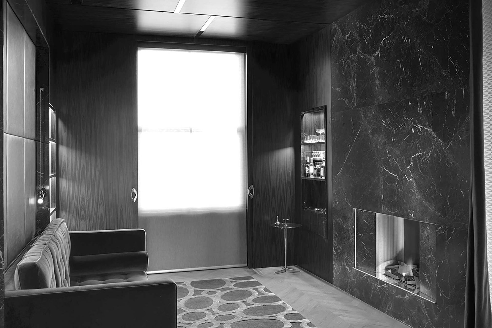 Dark luxury lounge with a marble feature wall and no visible speakers, sound delivered by invisible Amina panels