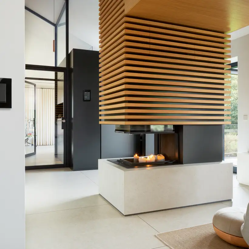 Modern living room with a fireplace and a JUNG KNX control panel on the wall