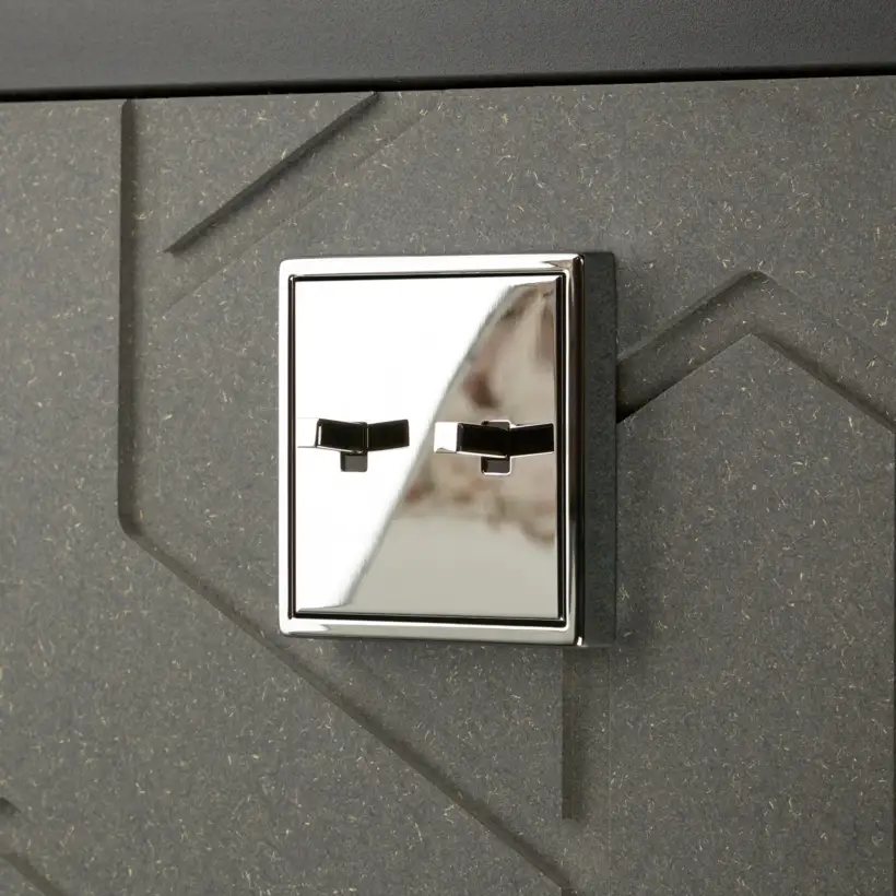 JUNG LS 1912 two-gang toggle switch in polished chrome on a dark textured wall