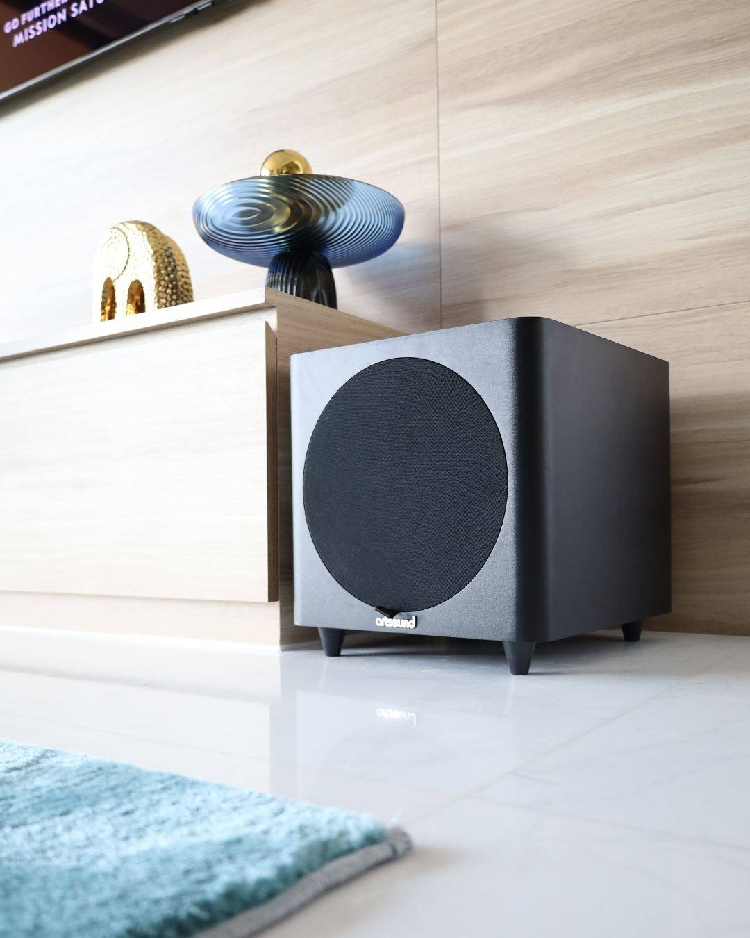 Black Artsound subwoofer next to a media console with decorative pieces in an Atlantis apartment