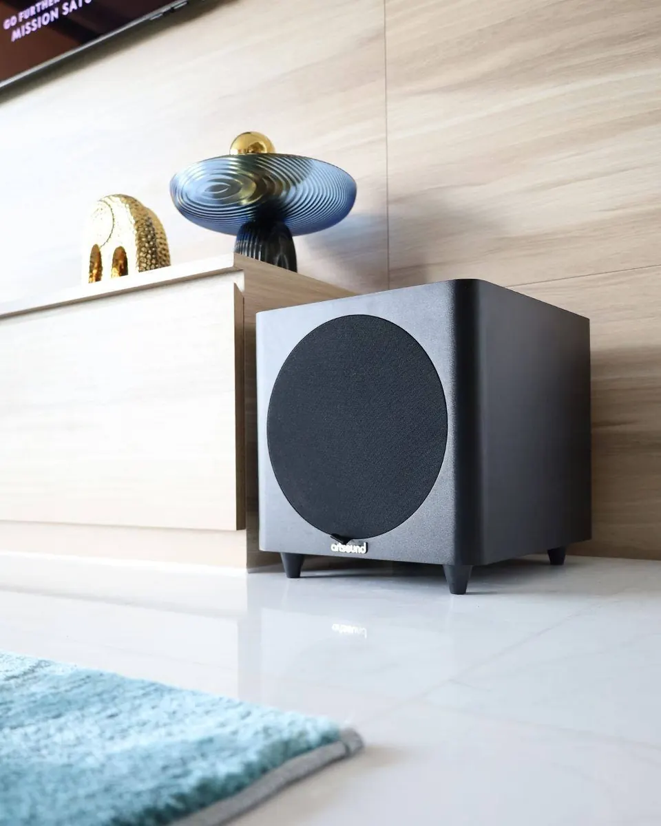 Black Artsound subwoofer next to a media console with decorative pieces in an Atlantis apartment
