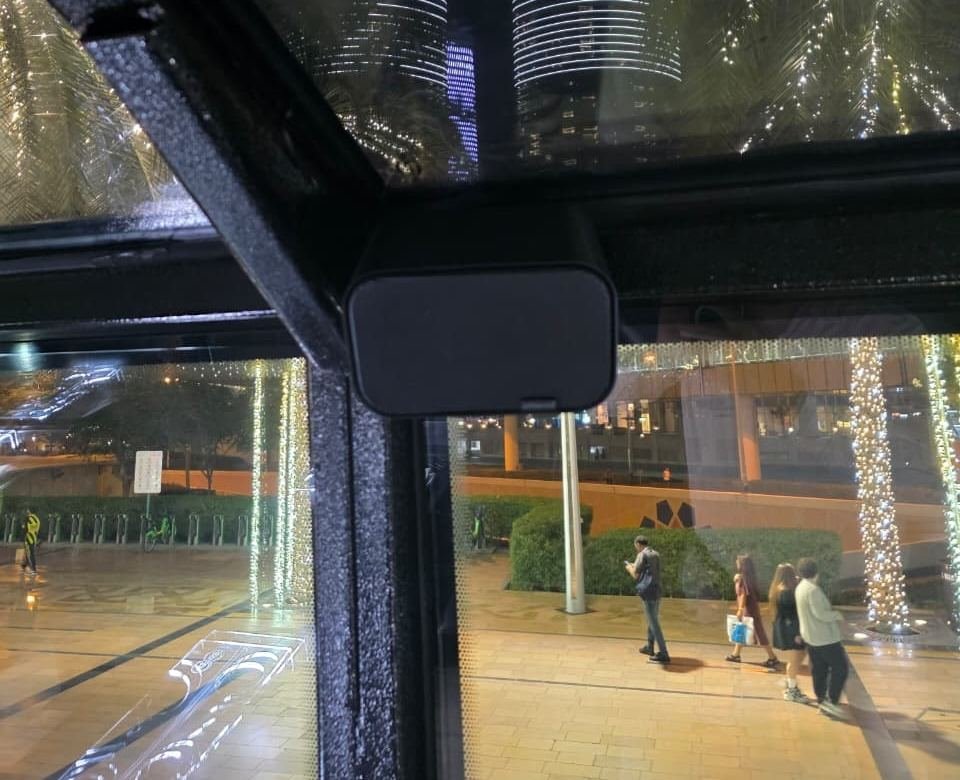 Artsound speaker mounted near the bus window with the Dubai skyline visible outside at night