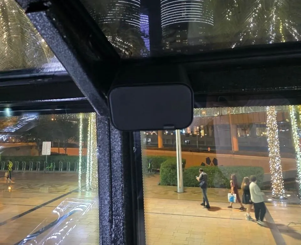 Artsound speaker mounted near the bus window with the Dubai skyline visible outside at night