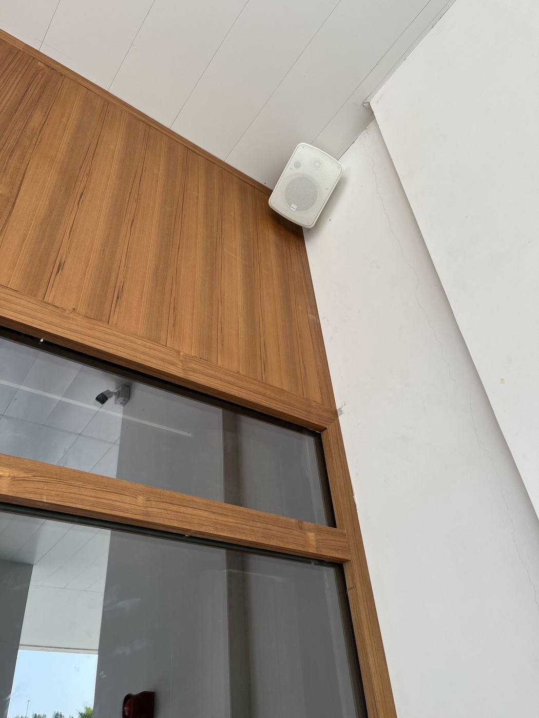 Artsound outdoor speaker mounted under a wood-paneled entrance eave at an Al Barari café