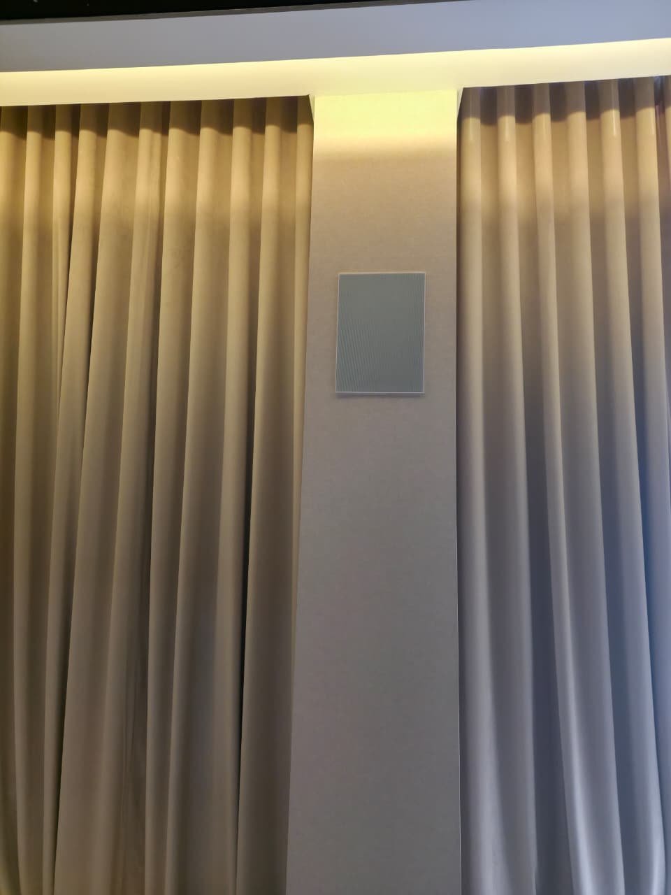 Artsound RE series on-wall speaker installed between curtains as part of a home cinema setup