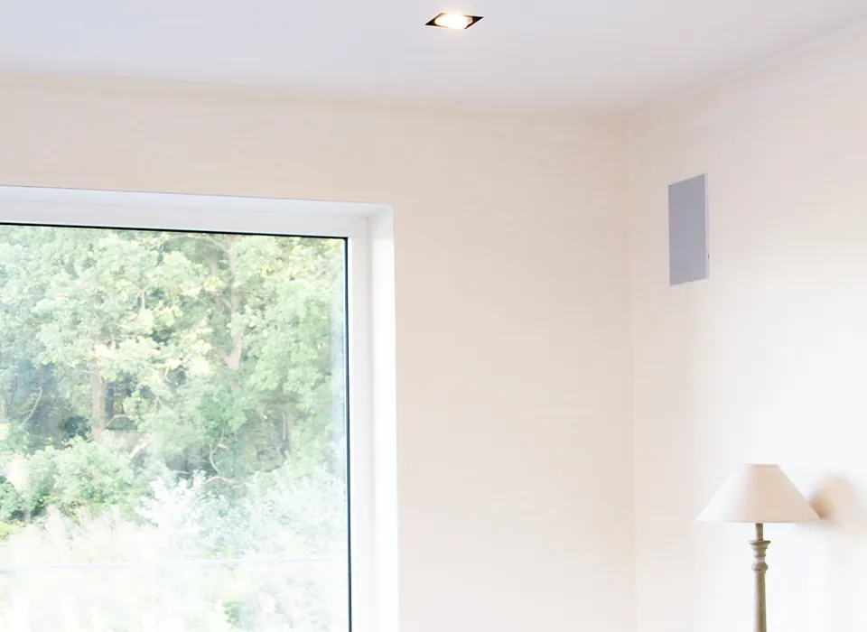 White Artsound in-wall speaker finished flush with the wall of a bright living room