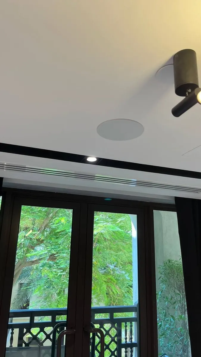 In-ceiling speaker on an office balcony ceiling with spotlight and greenery