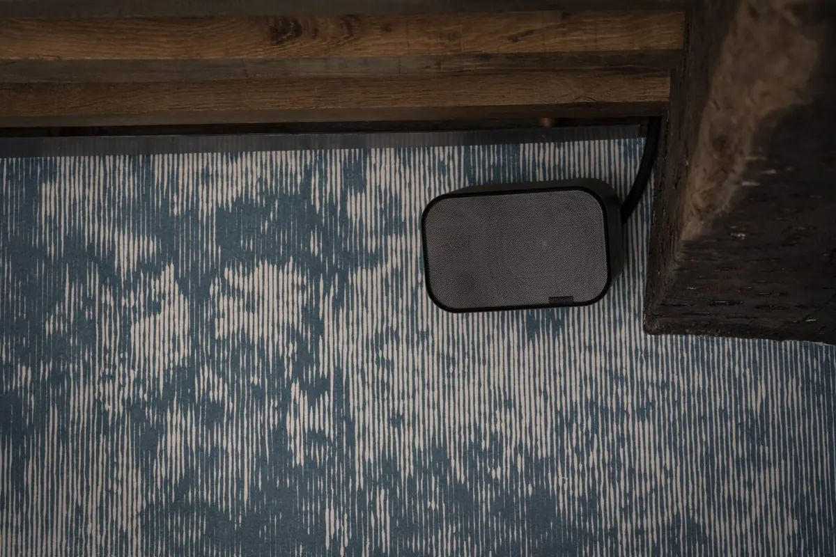 Black Artsound on-wall speaker with its cable running up out of sight