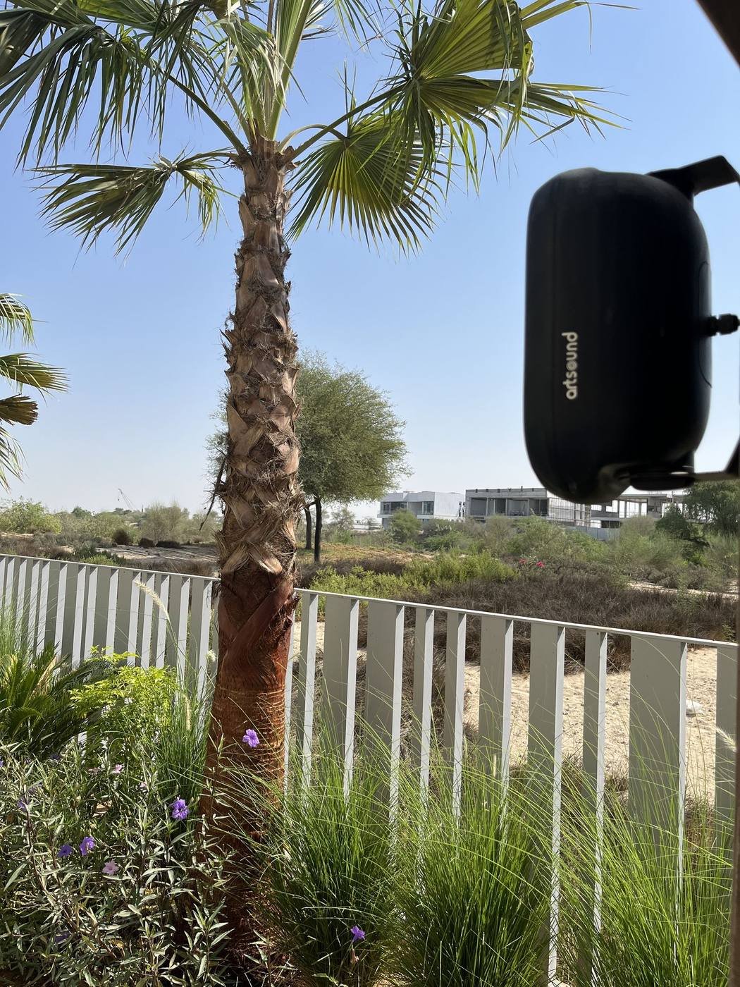 Artsound outdoor speaker mounted near a palm tree in a Dubai Hills villa garden